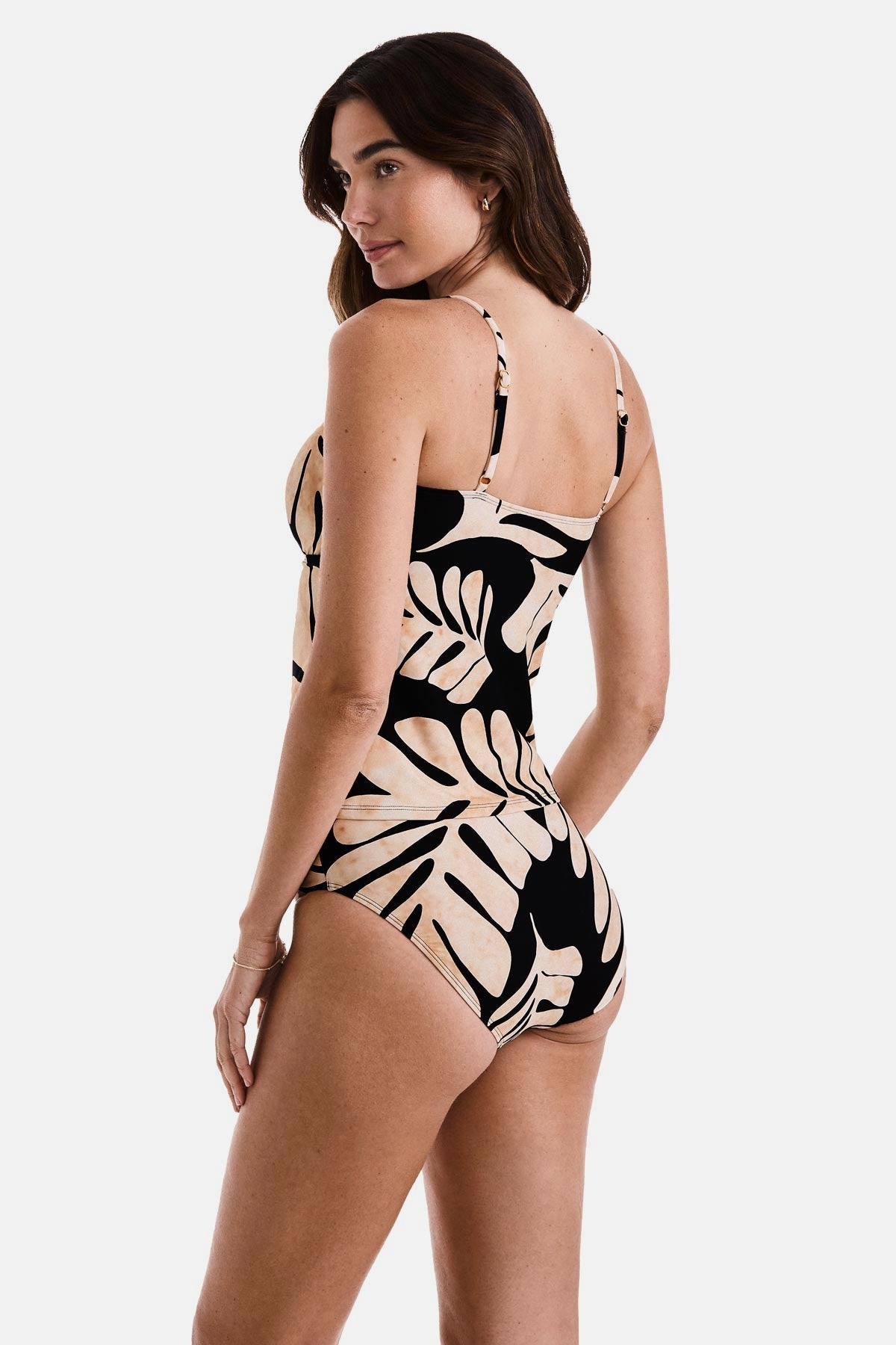 Woman turned left wearing a large tan and black leaf printed tankini top with matching swim bottoms