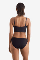 Woman faced away wearing a black midkini swim top with black swim bottoms