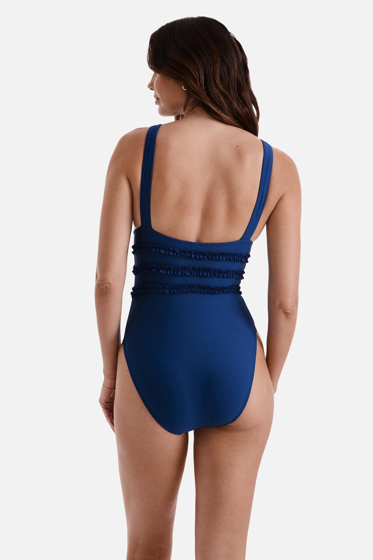 Woman turned away wearing a dark blue one-piece swimsuit with ruffles on the waist