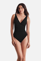 Woman wearing a black one-piece swimsuit with frills on the edges